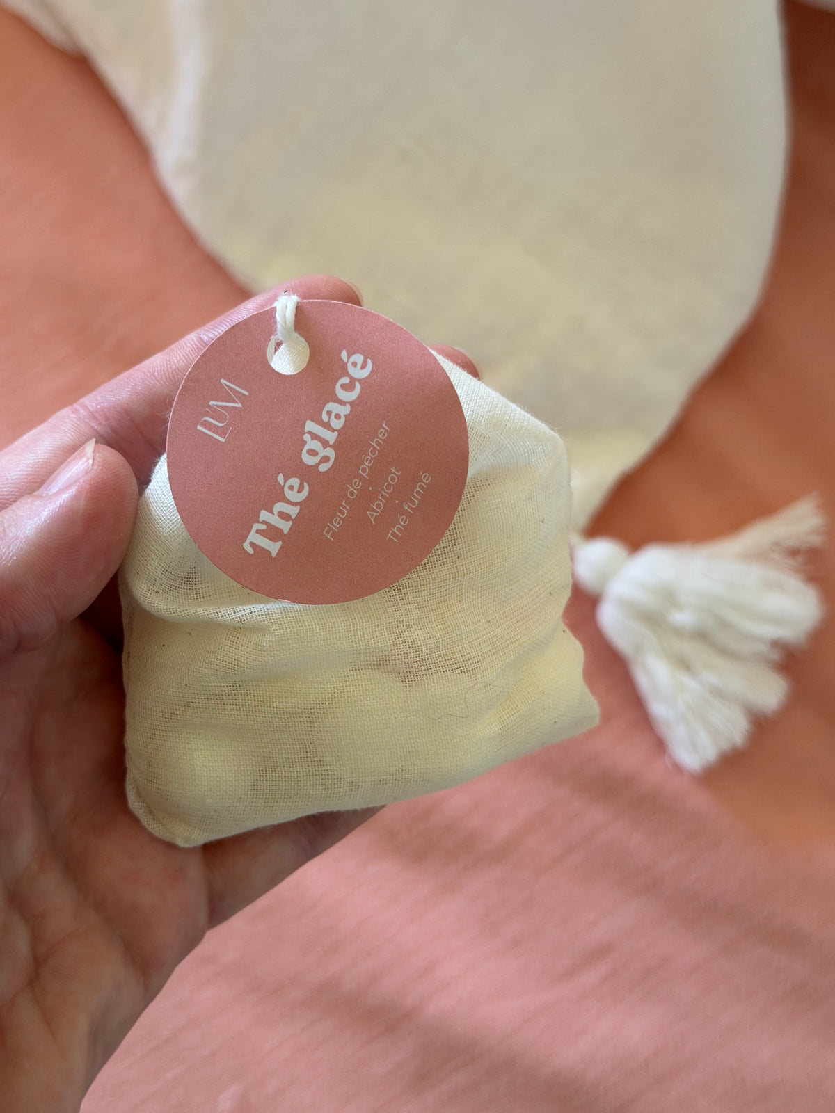 main qui tient le sachet en coton parfumé thé glacé LUM